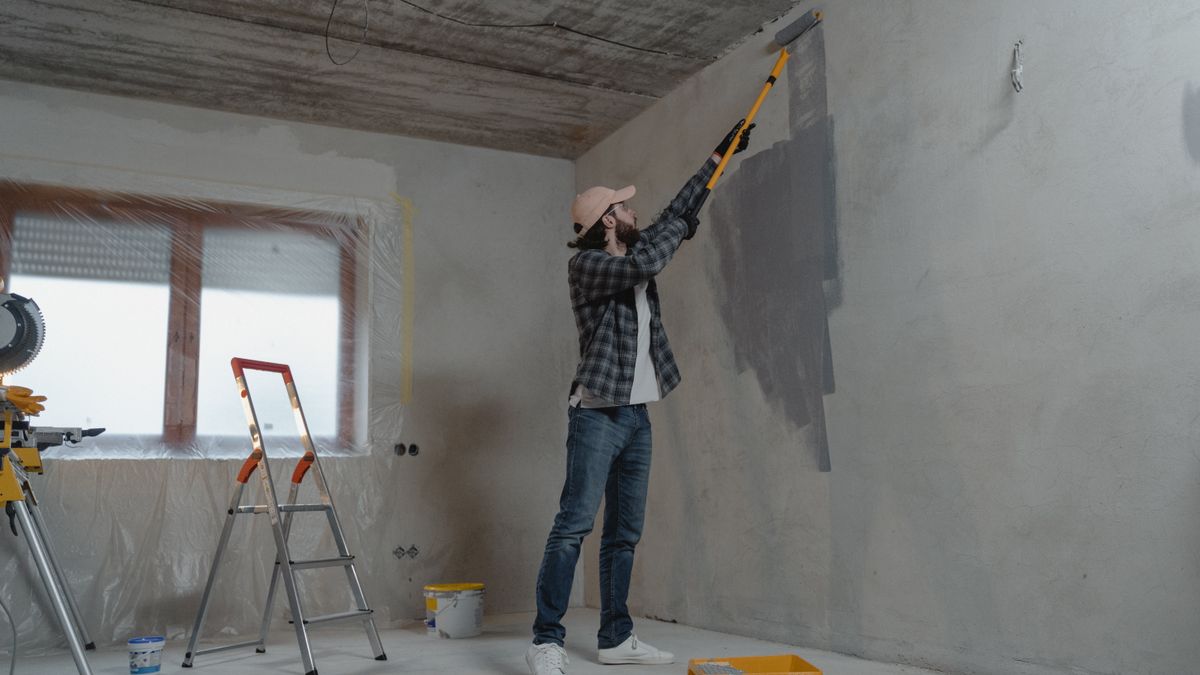A painter rolling off a new roller cover on a paint tray